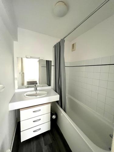 une salle de bain blanche avec un lavabo et une baignoire dans l'établissement Aigues Marines - Appartement spacieux avec parking et terrasse, à Aytré