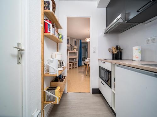 une cuisine avec des comptoirs blancs et un couloir dans l'établissement T de la Foux N 51 - 2P5C, à Allos