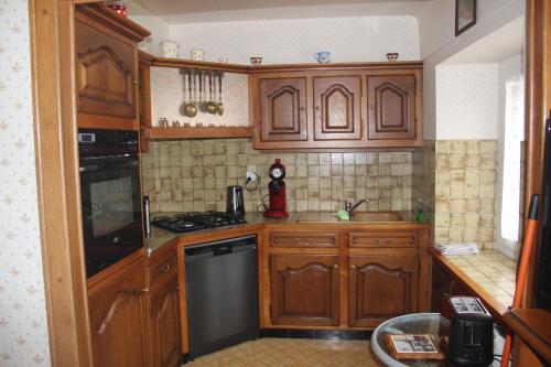 - une cuisine avec des placards en bois et un lave-vaisselle noir dans l'établissement Chez Gilles et Christine, à Mieussy