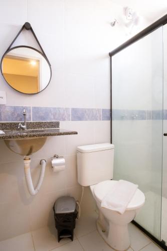 a bathroom with a toilet and a sink and a mirror at Marezzi Hotel Aracaju in Aracaju