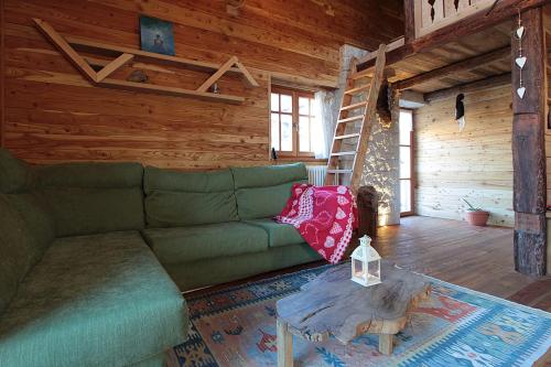 a living room with a green couch and a ladder at Chalet Incanto, Frassilongo, Trentino Alto Adige in Frassilongo
