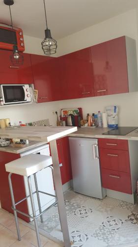 une cuisine avec des armoires rouges et un comptoir blanc dans l'établissement Charming Studio near Paris, à Montrouge