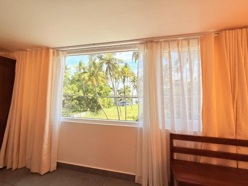 a bedroom with a window with a view of a palm tree at Golden Sands Cherai in Cherai Beach
