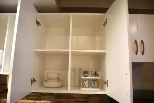 a white cupboard with plates and dishes in it at Marilao Bulacan VIP flat in Lias