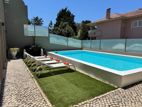 a swimming pool with two lounge chairs next to a house at Estoril 17 in Estoril