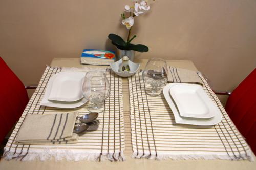 a table with plates and glasses and a vase with flowers at Sweet Home in Dimona
