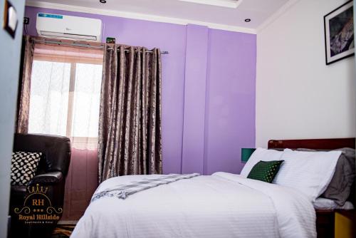 a bedroom with purple walls and a bed and a window at Royal Hillside Apartments and Hotels in Yaoundé