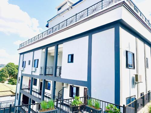 a white and blue building with plants on the balconies at Royal Hillside Apartments and Hotels in Yaoundé