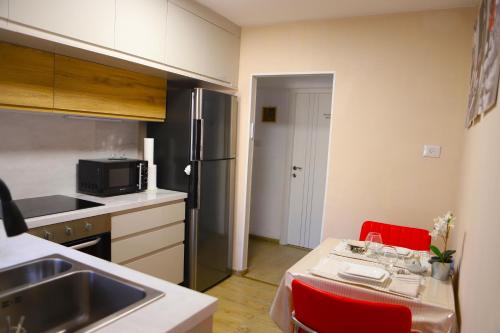 a small kitchen with a table and red chairs at Sweet Home in Dimona