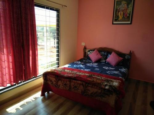 a bedroom with a bed and a window with red curtains at Patankar Nest Homestay in Helwāk