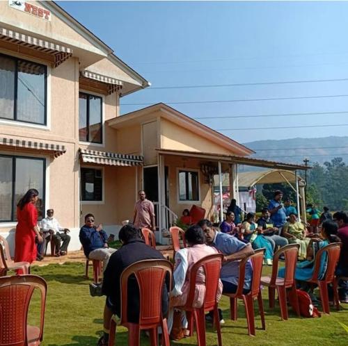 un grupo de personas sentadas en sillas frente a una casa en Patankar Nest Homestay, en Helwāk