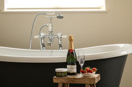 a bottle of champagne on a table next to a bath tub at Hill View in Burford