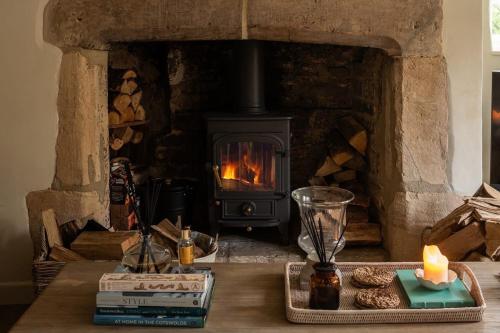 a stone fireplace with a stove with cookies on a table at Hill View in Burford