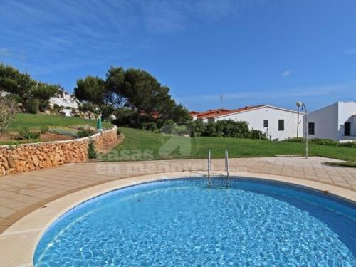 a large blue swimming pool in front of a house at House with sea views and pool in Arenal del Castell in Arenal d'en Castell