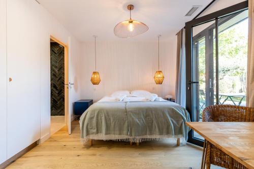 a bedroom with a bed and a table and a window at Villa Agapi - 10 personnes, piscine chauffée, pétanque - Lège cap Ferret in Lège-Cap-Ferret