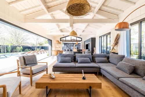 a living room with a couch and a table at Villa Agapi - 10 personnes, piscine chauffée, pétanque - Lège cap Ferret in Lège-Cap-Ferret