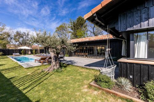 a house with a yard with a tree and a swing at Villa Agapi - 10 personnes, piscine chauffée, pétanque - Lège cap Ferret in Lège-Cap-Ferret