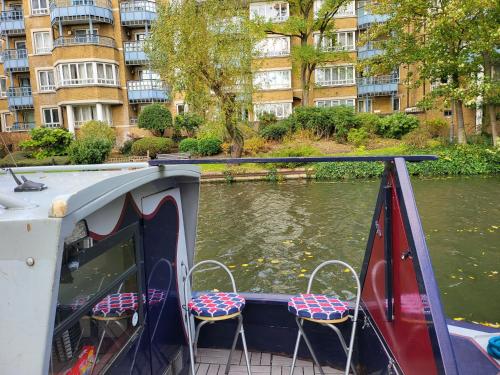 Un barco con dos sillas al lado de un río. en Comfy Canal in Little Venice for Family & Friends, en Londres