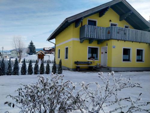 a yellow house in the snow with christmas trees at Appartement Kieler in Haus im Ennstal