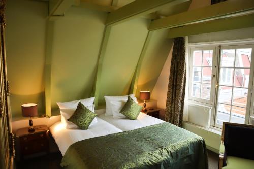 a bedroom with a bed with green walls and a window at Ambassade Hotel in Amsterdam