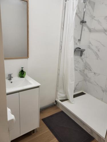 une salle de bain blanche avec une douche et un lavabo dans l'établissement charment appartement au pied de trame, au Mans