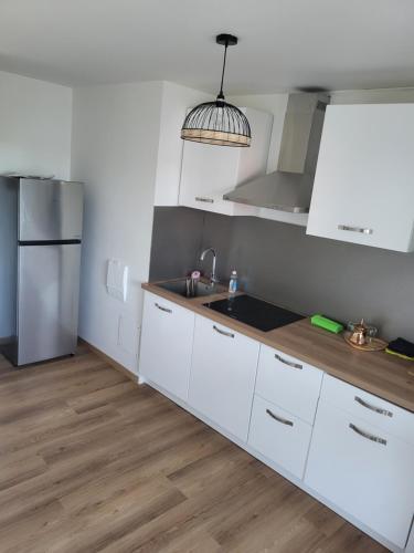 une cuisine avec des armoires blanches et un réfrigérateur en acier inoxydable dans l'établissement charment appartement au pied de trame, au Mans