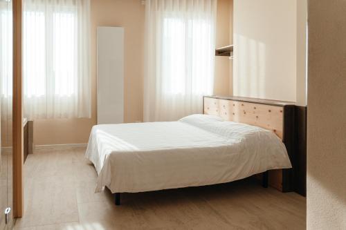 a bedroom with a bed with white sheets and windows at Wine & Wellness in Villalta