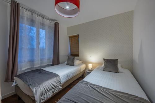 two beds in a room with a window at LOGIS DU GRAND PIN in Saint-Martin-des-Entrées