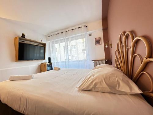 Cette chambre comprend un grand lit blanc et une télévision. dans l'établissement Le Théâtre studio cosy en coeur de ville, à Limoges