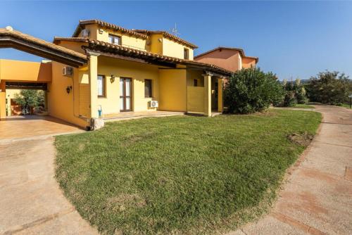 a yellow house with a green lawn in front of it at Il Mirto Appartamenti, Ac e Wifi, Gallura in Vignola Mare
