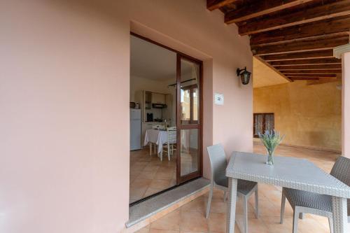 a dining room with a white table and a kitchen at Il Mirto Appartamenti, Ac e Wifi, Gallura in Vignola Mare