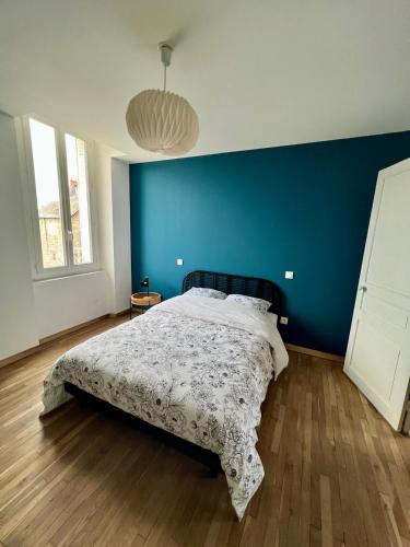 une chambre avec un lit avec un mur bleu dans l'établissement Casa Zola - T3 - Clim Balcon - Centre Brive, à Brive-la-Gaillarde