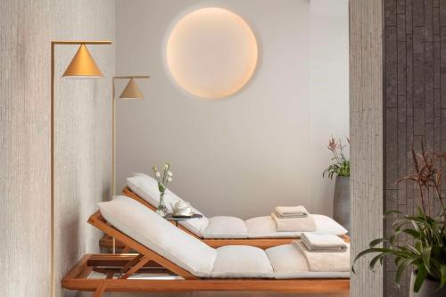 a living room with white furniture and a large light fixture at Anantara Grand Hotel Krasnapolsky Amsterdam in Amsterdam