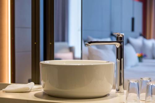 a white sink with a faucet on a counter at Anantara Grand Hotel Krasnapolsky Amsterdam in Amsterdam