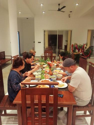 a group of people sitting around a table eating food at Sea Wind Villa Thalpe in Talpe