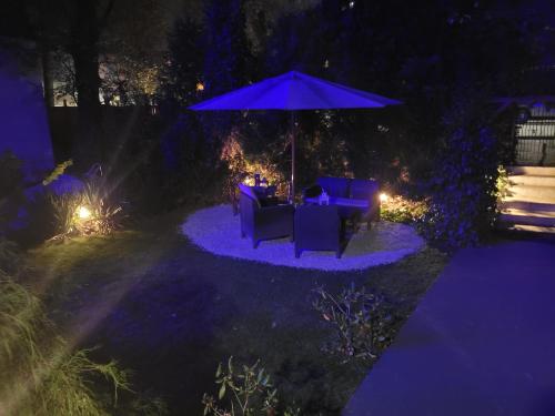 a patio with chairs and an umbrella at night at Willa Nad Potokiem in Kudowa-Zdrój