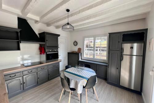 une cuisine avec des placards gris et une table avec des chaises dans l'établissement Villa Pougeol - 6 pers - PiscineBarbecuePétanque, à Chanac-les-Mines
