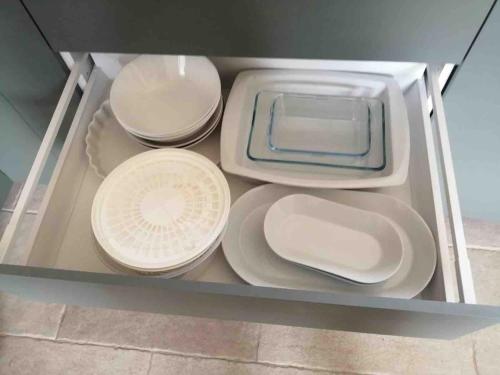 a drawer filled with white plates and bowls at Maison rénovée - jacuzzi et cheminée in Saint-Samson-de-la-Roque