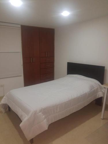 a bedroom with a bed and a wooden cabinet at Cálida Casa Zil&Li coliving Tunja in Tunja