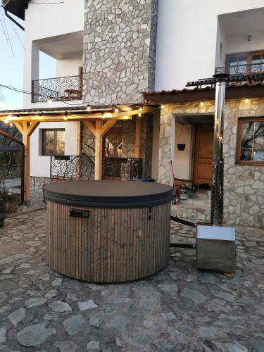 a stone house with a large tub in front of it at Pensiunea Codruta in Carpinis