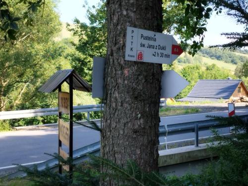 a sign on a tree next to a road at Agroturystyka Pod Gruszą in Chyrowa