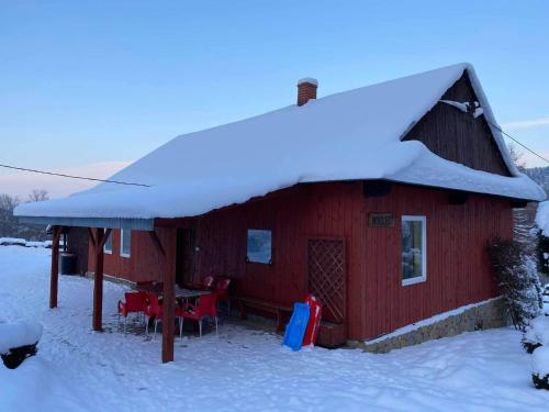 a red cabin with snow on top of it at Agroturystyka Pod Gruszą in Chyrowa