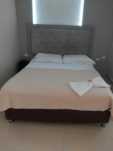a large bed with white sheets and pillows on it at Villa Mary Hostal in Barranquilla