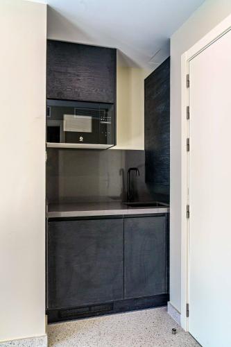 a kitchen with black cabinets and a microwave at SUNSET MALAGA - PRIME & DESIGN in Málaga