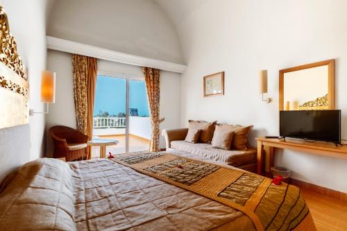 a bedroom with a large bed and a living room at Iris Hotel & Thalasso in Taguermess