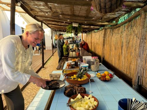 サグレスにあるAlgarve Surf Camp & Hostel Sagresの食卓前に立つ女