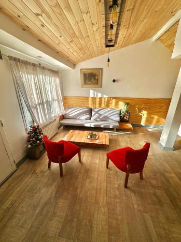 a living room with a couch and two red chairs at Hostel TRUFA in San Carlos de Bariloche