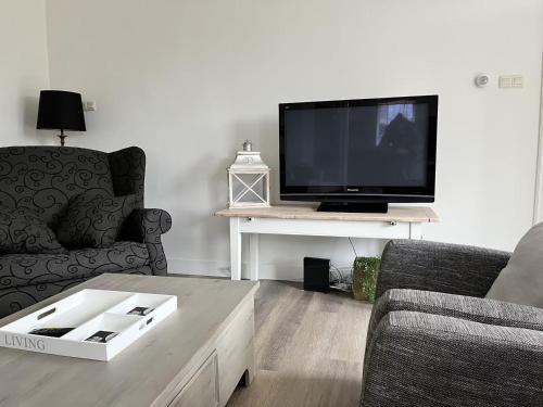 a living room with a tv and a couch and a table at Vakantiebungalow Limmen in Limmen