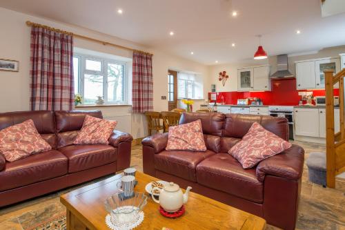 a living room with two leather couches and a kitchen at Teifi Cottage in Cardigan