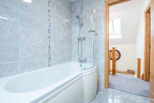 une salle de bain avec une baignoire blanche et une douche dans l'établissement Teifi Cottage, à Cardigan